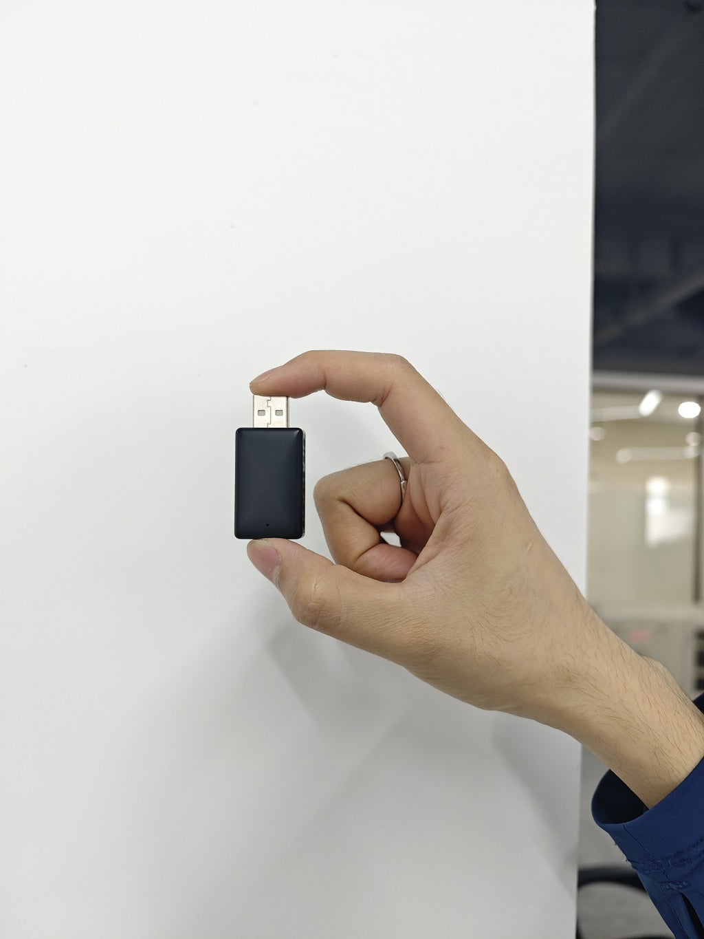 Wireless CarPlay adapter held between two fingers to show its size