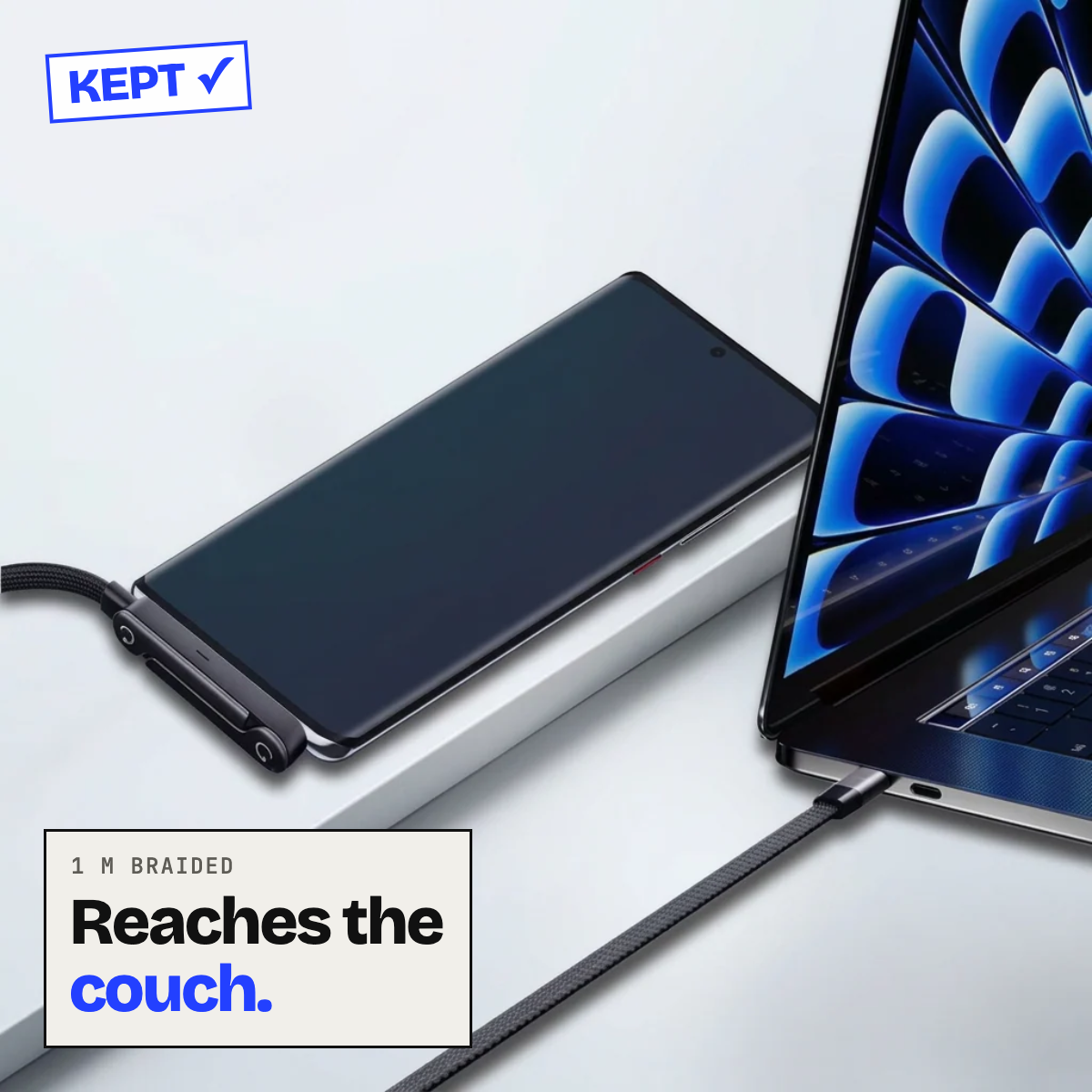 Braided cable charging a phone beside a laptop
